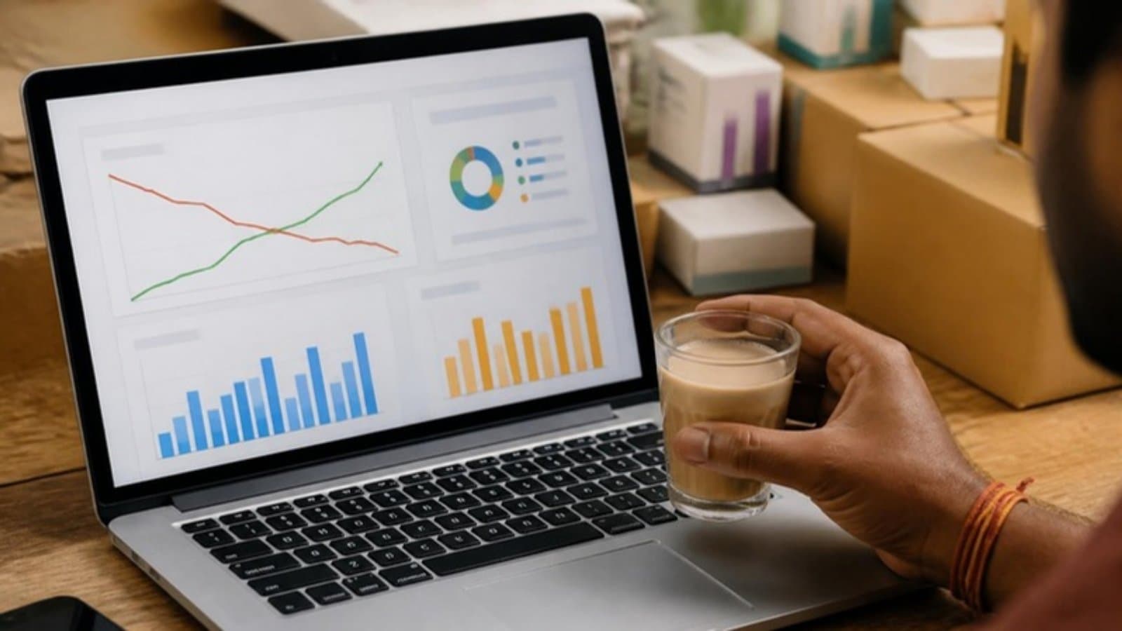 Amazon advertising dashboard on a laptop with falling cost and rising sales lines